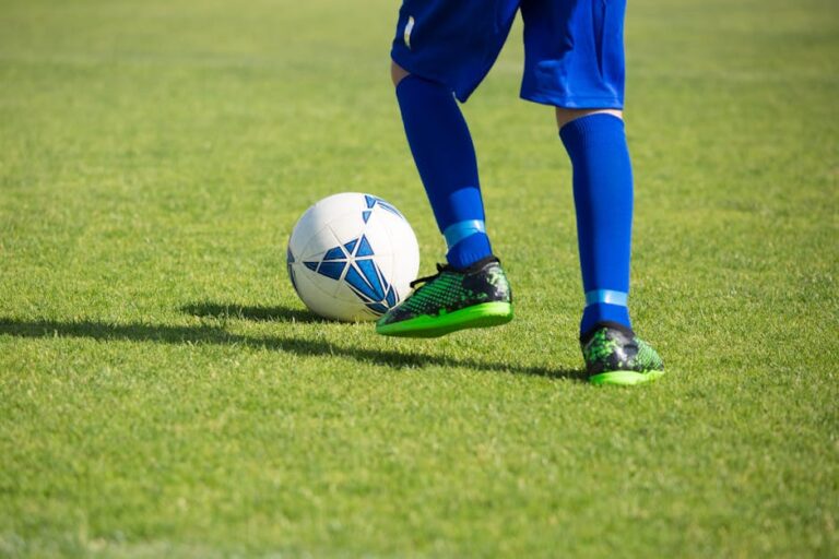 Close-up of a soccer player dribbling a ball on a vibrant green field in Portugal.