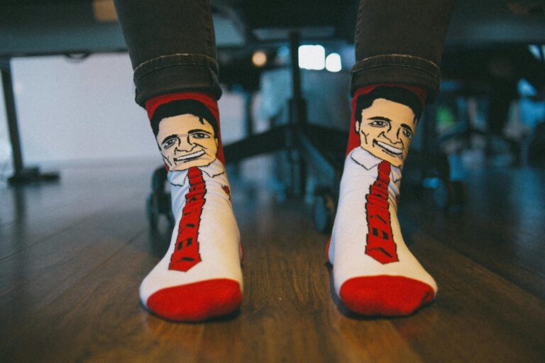 Close-up of colorful character socks on a wooden floor under a desk in an office setting.